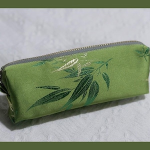 May include: A green zippered pouch with a floral pattern. The pouch is made of a soft, silky fabric and has a subtle sheen.