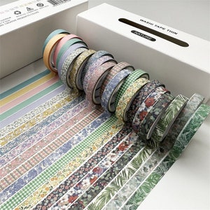 May include: A set of 15 washi tapes in a variety of floral and geometric patterns. The tapes are arranged in a fan shape and are all thin and delicate. The tapes are labeled "Washi Tape Thin" and "Nature".