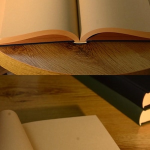 Puede incluir: Dos cuadernos abiertos en blanco con p&aacute;ginas de papel marr&oacute;n y una cubierta azul oscuro. Los cuadernos est&aacute;n sobre una mesa de madera.