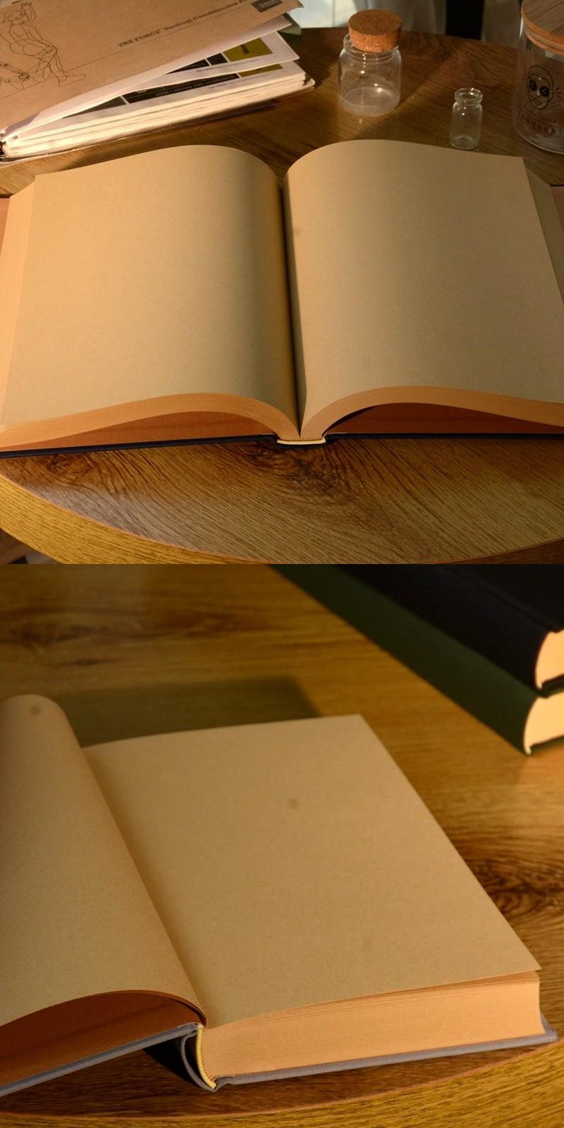 Puede incluir: Dos cuadernos abiertos en blanco con p&aacute;ginas de papel marr&oacute;n y una cubierta azul oscuro. Los cuadernos est&aacute;n sobre una mesa de madera.