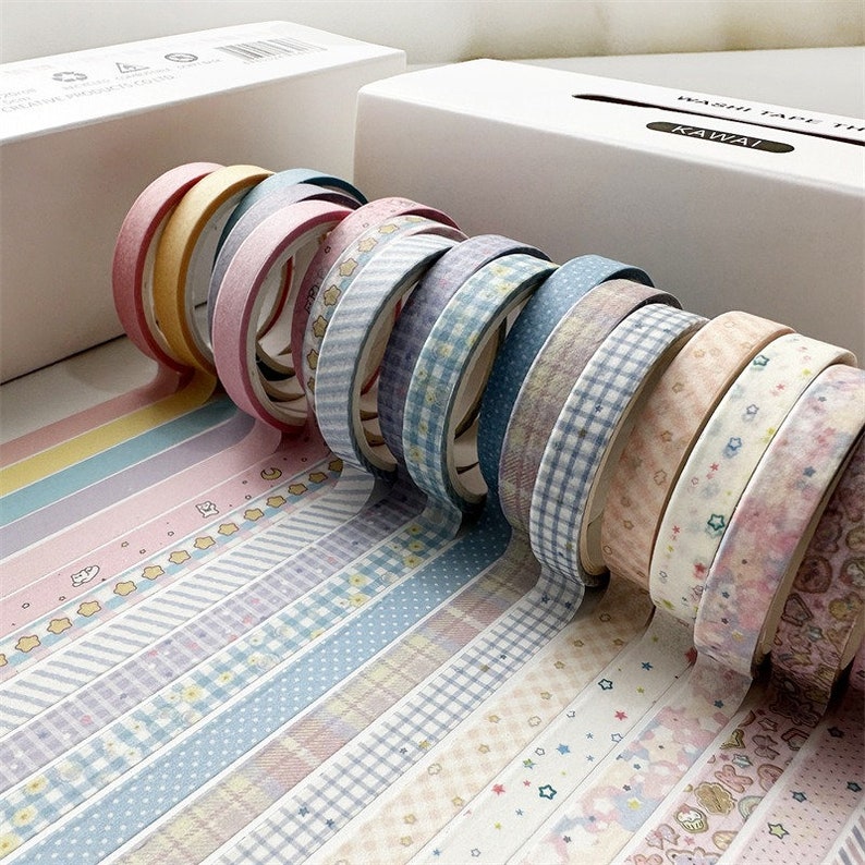 May include: A collection of colorful washi tapes with various patterns, including stars, stripes, polka dots, and plaid. The tapes are rolled up and arranged in a row, with the ends of the tapes showing the different patterns.