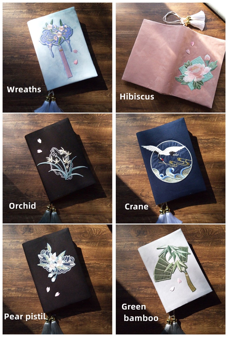 May include: Six different book covers with embroidered designs. The covers are made of a variety of fabrics, including blue, pink, black, and white. The designs include wreaths, hibiscus, orchids, cranes, pear pistils, and green bamboo.