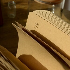 May include: A brown notebook with the number 179 printed on the spine. The notebook is open and the pages are fanned out.