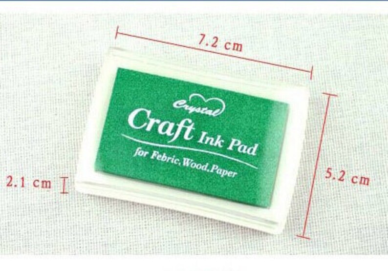 K&ouml;nnte beinhalten: Ein gr&uuml;nes Bastel-Stempelkissen in einem durchsichtigen Plastikgeh&auml;use. Das Stempelkissen ist mit "Crystal Craft Ink Pad" und "for Febric, Wood, Paper" beschriftet. Das Stempelkissen misst 7,2 cm x 5,2 cm.