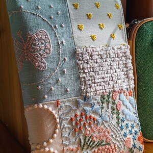 May include: A patchwork fabric notebook cover with embroidered designs. The cover features a butterfly, flowers, and geometric patterns in shades of blue, pink, yellow, and orange.