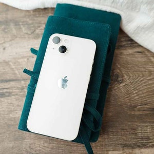 May include: A white iPhone with a green case. The phone has a camera lens with two circles and an Apple logo.