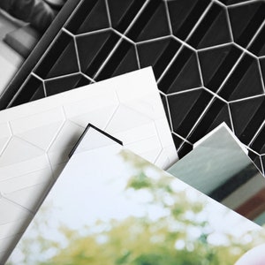 Może przedstawiać: Trzy arkusze papieru z geometrycznym wzorem. G&oacute;rny arkusz jest czarny z wypukłym sześciokątnym wzorem. Środkowy arkusz jest biały z wypukłym sześciokątnym wzorem. Dolny arkusz jest biały z rozmytym obrazem zielonych liści.