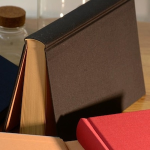 Puede incluir: Tres libros de tapa dura con cubiertas de diferentes colores. El libro de arriba tiene una cubierta de color marr&oacute;n oscuro, el libro del medio tiene una cubierta de color marr&oacute;n claro y el libro de abajo tiene una cubierta de color rojo.