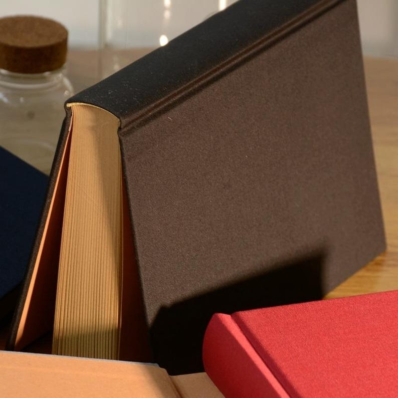 Puede incluir: Tres libros de tapa dura con cubiertas de diferentes colores. El libro de arriba tiene una cubierta de color marr&oacute;n oscuro, el libro del medio tiene una cubierta de color marr&oacute;n claro y el libro de abajo tiene una cubierta de color rojo.
