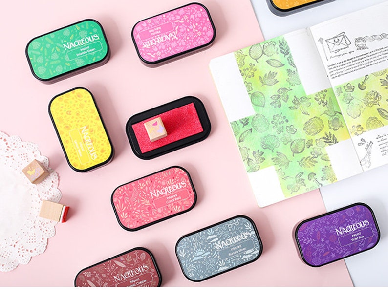 May include: Assortment of ten ink pads with different floral patterns and colors, including green, pink, red, blue, and gray. Each pad has the word "Nacreous" printed on it.