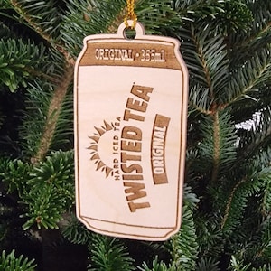 May include: Wooden ornament shaped like a can of Twisted Tea hard iced tea. The can is brown and has the words "Twisted Tea" and "Original" on it. The can is 355 ml.