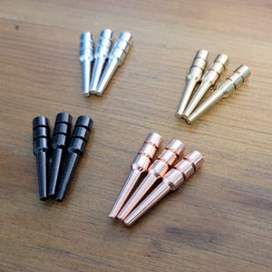 May include: Four sets of three metal knitting needles in silver, gold, black, and rose gold.
