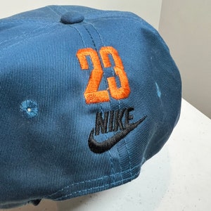 May include: A blue baseball cap with an orange embroidered number "23" and a black embroidered Nike logo.