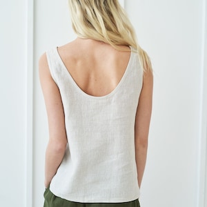 Könnte beinhalten: Eine Frau trägt ein hellbeiges Leinen-Tanktop und eine dunkelgrüne Leinenhose. Das Tanktop hat einen runden Ausschnitt und eine lockere Passform. Die Hose hat eine hohe Taille und eine lockere Passform.