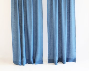 May include: Two blue linen curtains hanging from a rod. The curtains are a solid color and have a subtle texture.