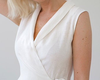 Puede incluir: Un vestido blanco de lino con cuello en V y un lazo en la cintura.
