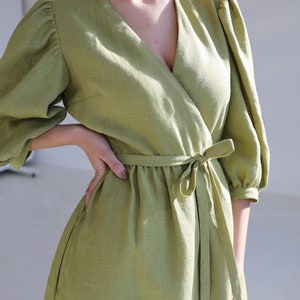 Puede incluir: Un vestido cruzado verde claro con escote en V y mangas cortas abullonadas. El vestido presenta un cintur&oacute;n de tela a juego atado a la cintura. El vestido est&aacute; hecho de una tela texturizada.