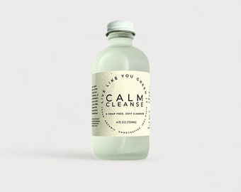 May include: A clear glass bottle with a white lid and a white label that says "Live Like You Green" and "Calm Cleanse" in a circle. The label also says "A soap free, easy cleanser" and "4 fl oz (120ml)".