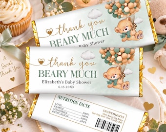 May include: Two rectangular candy bar wrappers with gold foil ends. The front features a teddy bear holding a cluster of sage green and beige balloons, clouds, and the text "thank you BEARY MUCH Elizabeth's Baby Shower 6.15.20XX". The back shows a nutrition facts label.