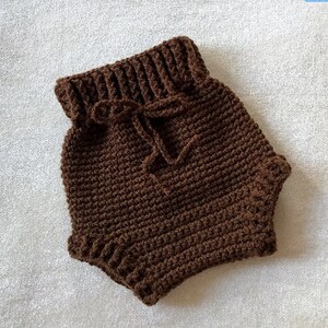 Puede incluir: Bombachos de beb&eacute; de crochet marr&oacute;n con cintura de cord&oacute;n.