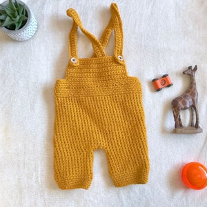 May include: A mustard yellow crocheted baby overall with straps and buttons.