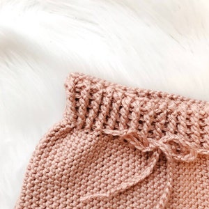 Puede incluir: Un gorro de beb&eacute; de ganchillo de color rosa suave con un cord&oacute;n de ajuste.