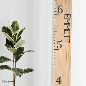 May include: A wooden growth chart with a ruler and the name "Emmett" printed on it. The chart is light brown with black markings.