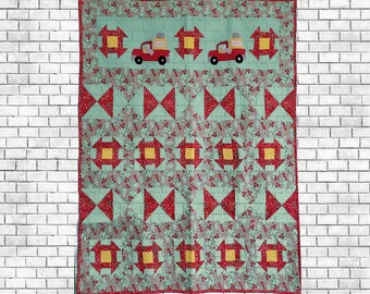 May include: A green and red patchwork quilt with a floral pattern. The quilt features a repeating pattern of squares and triangles. The quilt has a truck with the word "Peanut" on it in the top center.