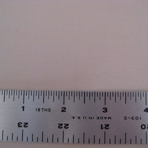May include: A silver metal ruler with black markings. The ruler is marked with inches and 16ths of an inch. The ruler is labeled "Made in U.S.A." and has the numbers 20, 21, 22, 23, and 24 printed on it.