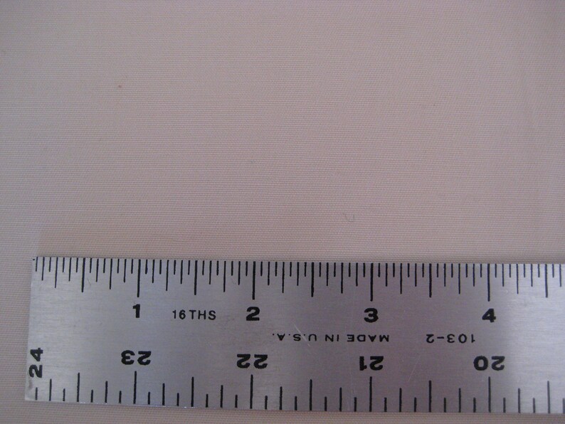 May include: A silver metal ruler with black markings. The ruler is marked with inches and 16ths of an inch. The ruler is labeled "Made in U.S.A." and has the numbers 20, 21, 22, 23, and 24 printed on it.