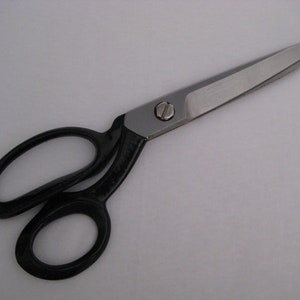 May include: A pair of black handled scissors with a silver blade. The scissors are open and the blade is pointed.