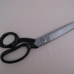 May include: Black handled fabric shears with a silver blade. The shears are approximately 10 inches long.