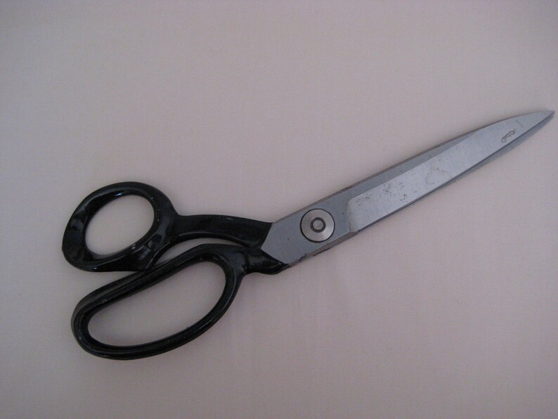 May include: Black handled fabric shears with a silver blade. The shears are approximately 10 inches long.