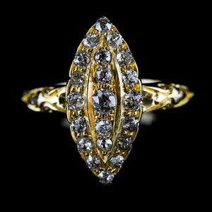 May include: A gold ring with a teardrop-shaped setting featuring a row of diamonds. The ring has a delicate, intricate design.