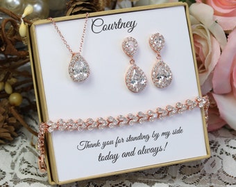 May include: A gift box with a rose gold necklace, earrings, and bracelet. The box has a white card with the text "Courtney" and "Thank you for standing by my side today and always!"
