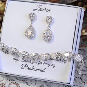 May include: A white gift box with a silver bracelet and earrings. The box has the name "Lauren" written on it and the message "Thank you for being my bridesmaid."