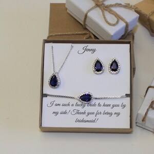 May include: A gift box with a blue teardrop necklace, earrings, and bracelet set. The box has a card inside that says "Jenny I am such a lucky bride to have you by my side! Thank you for being my bridesmaid!"
