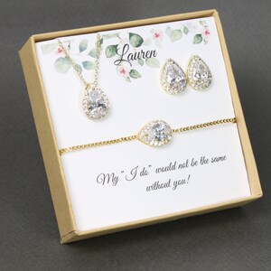May include: A gift box with a gold necklace, earrings, and bracelet with pear-shaped clear stones. The box has a floral design and the text "Lauren" and "My "I do" would not be the same without you!"