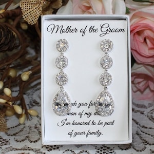 May include: A white gift box with a clear lid containing a pair of silver teardrop earrings with crystal accents. The box has a card inside that reads "Mother of the Groom" and "Thank you for the man of my dreams. I'm honored to be part of your family."