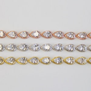 May include: Three rows of pear-shaped crystal bracelets in rose gold, silver, and gold settings.