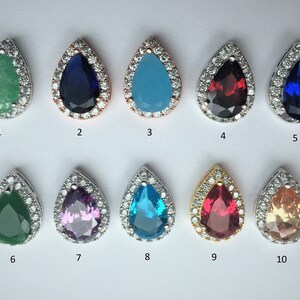 May include: Ten teardrop-shaped pendants with different colored gemstones surrounded by a halo of clear cubic zirconia stones. The pendants are numbered 1 through 10.