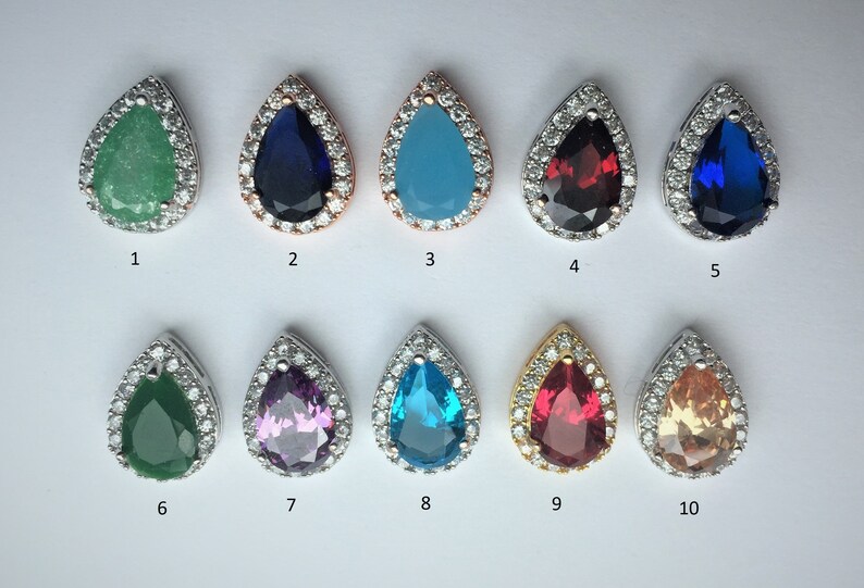 May include: Ten teardrop-shaped pendants with different colored gemstones surrounded by a halo of clear cubic zirconia stones. The pendants are numbered 1 through 10.