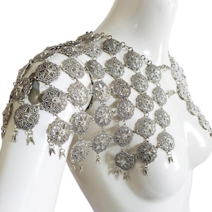 May include: Silver chain body jewelry with a floral design. The chain is made of metal links and has a delicate, feminine look.
