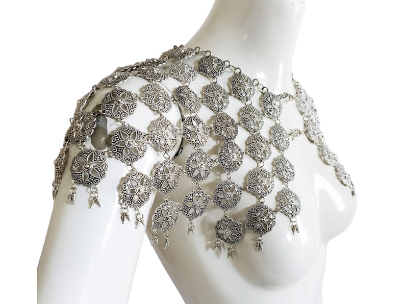 May include: Silver chain body jewelry with a floral design. The chain is made of metal links and has a delicate, feminine look.