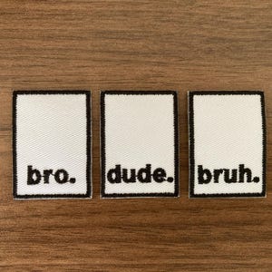 May include: Three rectangular embroidered patches with a white background and a black border. Each patch features black lowercase text: the first reads bro., the second reads dude., and the third reads bruh., all with a period at the end.