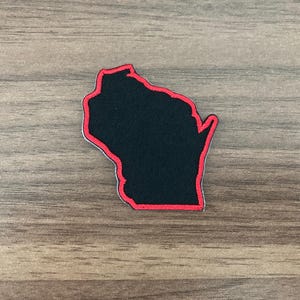 May include: A fabric patch shaped like the state of Wisconsin, featuring a solid black center with a vibrant red embroidered border outlining the entire perimeter of the state's geographic shape, creating a distinct and clear visual contrast.