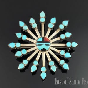 Könnte beinhalten: Eine Brosche aus Silber und Türkis in Form einer Sonnenstrahlenkrone mit einem geometrischen Design in der Mitte. Die Brosche ist aus Sterlingsilber gefertigt und verfügt über Türkis-Steine in verschiedenen Größen und Formen.