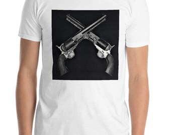 以下が含まれることがあります： 白のTシャツ。黒と白のグラフィックで、2丁のクロスしたリボルバーが描かれています。リボルバーは暗い銃身と銀色のアクセントがあり、黒い正方形の背景に配置されています。