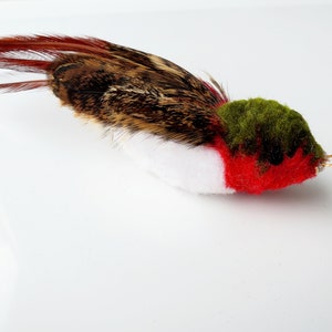 May include: A small, handmade felt bird ornament with brown and white feathers, a red and green body, and a gold string for hanging.