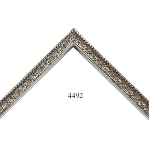 May include: A silver picture frame with an ornate design. The frame is in the shape of a corner and has the number 4492 printed on it.